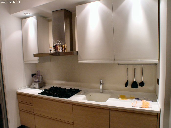 Qui vediamo bene il piano in Corian bianco con vasca ed alzatine integrate, una composizione molto pulita e ben studiata con prese al piano e faretti nelle giuste posizioni.
